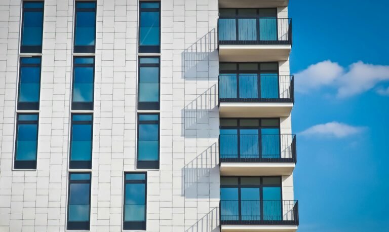 Home Contemporary urban apartment building with framed glass windows against clear blue sky.