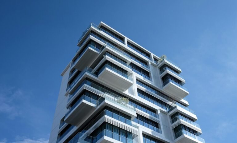 Home Striking low-angle shot of a modern condominium with unique balcony design and clear blue sky.